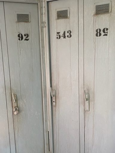 3 portes grises figurant des portes de vestiaire de type industriel.